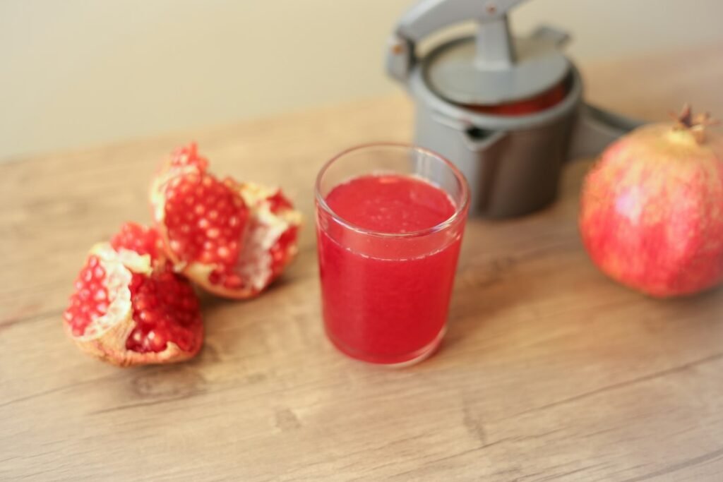 Strawberry Pomegranate Cooler for Summer Café Menus Pomegranate juice beside fresh fruit and a hand press